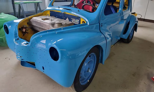 Blauer Oldtimer-Pkw ohne Motorhaube und Scheinwerfer in einer Werkstatt